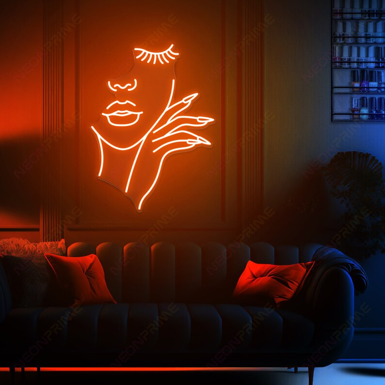 May include: A neon sign depicting a woman's face with her hand resting on her cheek. The neon is a bright orange colour and is mounted on a dark brown wall.