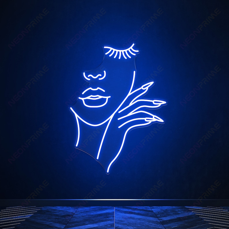 May include: A neon sign depicting a stylised outline of a woman's face with closed eyes and a hand resting on her chin. The sign is lit in a bright blue colour.