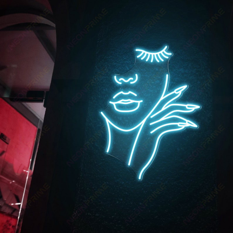 May include: A blue neon sign depicting a woman's face with her hand resting on her cheek. The sign is mounted on a black wall.