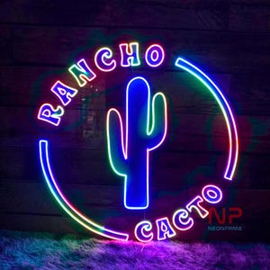 May include: A neon sign with a cactus and the words "Rancho Cacto" in a circle. The sign is lit up in multiple colors, including red, blue, green, and purple.