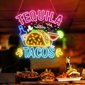 May include: Neon sign with the text "Tequila Tacos" in pink, blue, and yellow. The sign also features a cartoon image of a taco, a margarita, and a bottle of tequila.
