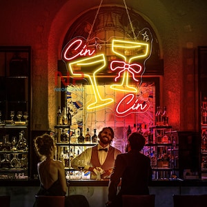 Pu&ograve; includere: Un'insegna al neon in un bar mostra due bicchieri da cocktail e la parola "Cin" in rosso e giallo. L'insegna &egrave; appesa sopra un bar con un barista e clienti. Il bar ha un'atmosfera classica e di lusso.