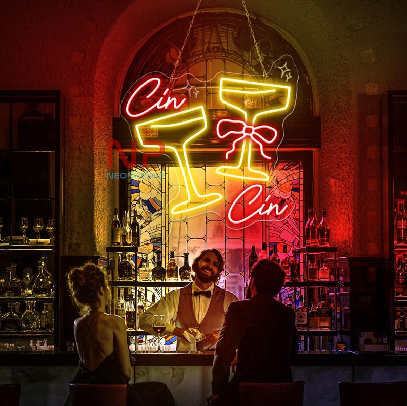 Pu&ograve; includere: Un'insegna al neon in un bar mostra due bicchieri da cocktail e la parola "Cin" in rosso e giallo. L'insegna &egrave; appesa sopra un bar con un barista e clienti. Il bar ha un'atmosfera classica e di lusso.
