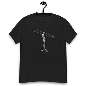 May include: Black t-shirt with a white outline illustration of a skeleton carrying a surfboard.