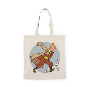 Puede incluir: Una bolsa de tela blanca con una imagen de dibujos animados de un hombre con un abrigo marrón y pantalones rojos corriendo con un perro blanco. El hombre tiene el pelo rojo y lleva un chaleco amarillo y una corbata azul.