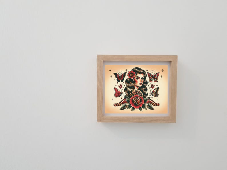 May include: A framed print of a woman with long dark hair and a red rose. She is surrounded by butterflies and stars. The print is in a light wood frame.