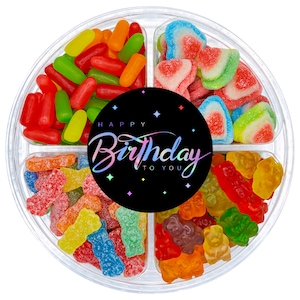 May include: A clear plastic container filled with assorted gummy candies. The container is divided into four sections. The top section has a black circle with the text "Happy Birthday to You". The other sections contain red, green, and yellow gummy worms, watermelon-shaped gummies, and gummy bears.