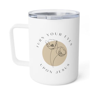 May include: White ceramic travel mug with a black handle and a beige circle with two black line drawings of flowers. The text "Turn your eyes upon Jesus" is written around the circle.