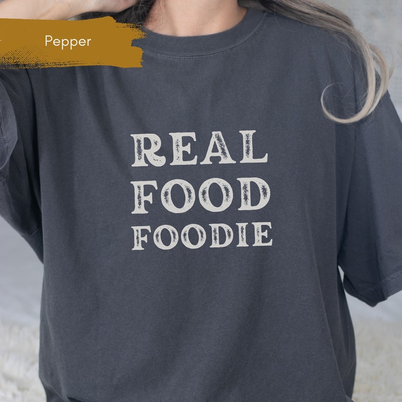 May include: A dark grey t-shirt with the text "REAL FOOD FOODIE" printed in white.