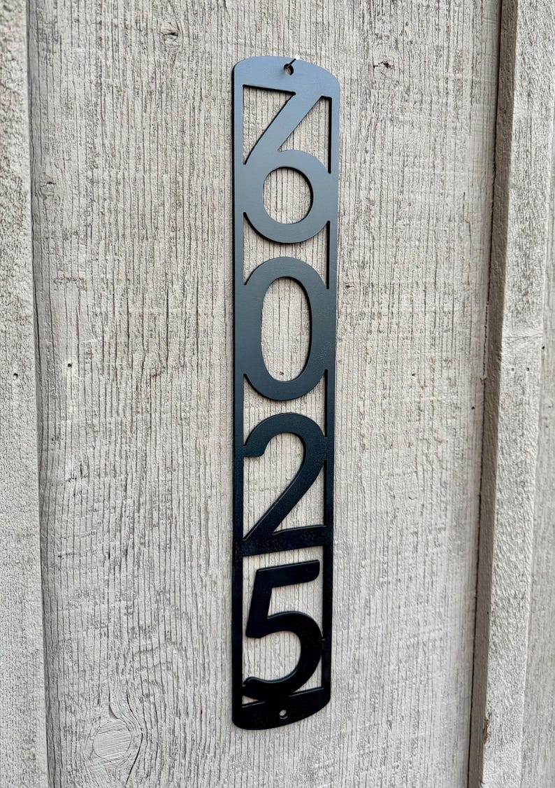 May include: Black metal house number plaque with the numbers 2025 displayed vertically.