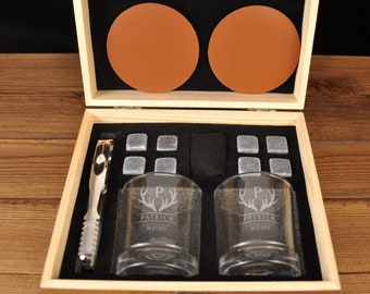 May include: A wooden box with a set of two personalized whiskey glasses, a set of whiskey stones, a pair of coasters, and a pair of tongs. The glasses are engraved with the name "Patrick" and a stag head design.
