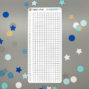 May include: A white sticker with a grid for tracking daily habits, labeled "Tablet & Quill" and "Year in Pixels." The sticker is surrounded by blue, teal, and gold star and circle confetti.