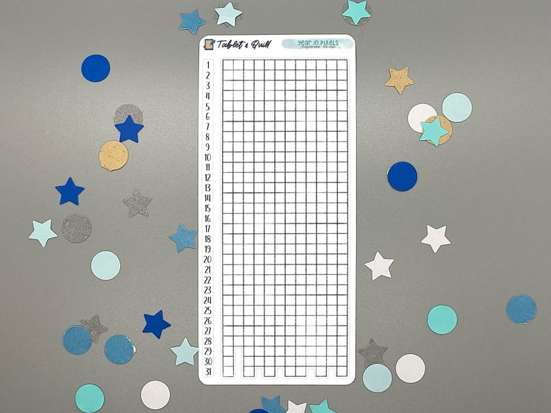 May include: A white sticker with a grid for tracking daily habits, labeled "Tablet & Quill" and "Year in Pixels." The sticker is surrounded by blue, teal, and gold star and circle confetti.