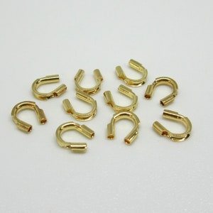 May include: A group of 10 gold-colored metal crimp end caps for jewelry making.