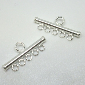 May include: Two silver-toned metal slider clasps with five jump rings each. The clasps are designed to be used for necklaces or bracelets.