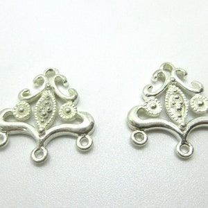 May include: Two silver-toned metal jewelry findings with a decorative, ornate design. Each finding has three loops at the bottom.