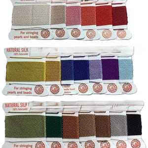 May include: A collection of spools of natural silk thread in various colors, including beige, pink, red, gold, blue, purple, and green. Each spool is labeled "NATURAL SILK" and "For stringing pearls and beads."