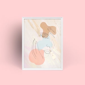May include: White framed art print with a minimalist line drawing of a face and abstract shapes in peach, blue, and brown. The artwork has a neutral colour palette and is set against a textured background.