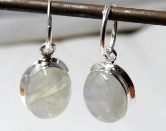May include: A pair of silver hoop earrings with oval-shaped moonstone gemstones. The earrings have a simple design and are perfect for everyday wear.