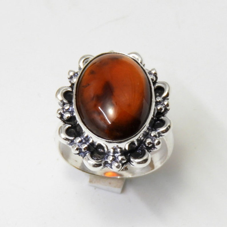 May include: A silver ring with an oval-shaped brown gemstone set in a decorative silver setting.