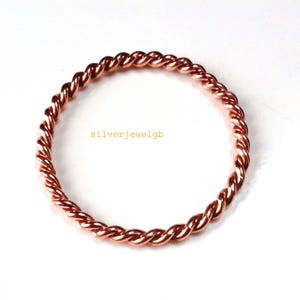 May include: A copper-colored, twisted ring. The ring is circular and has a braided design. The text "silverjewelgb" is visible on the white background. The ring is a jewelry item.