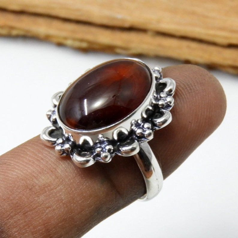 May include: A silver ring with a brown oval gemstone set in a floral design.