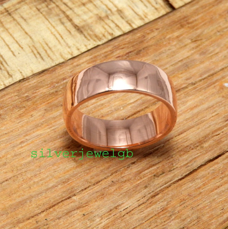 May include: A wide rose gold band ring with a polished finish.