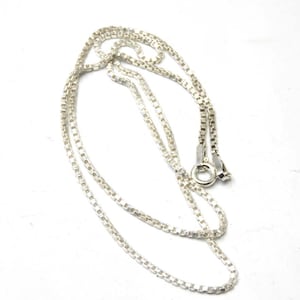May include: A silver chain necklace with a box chain style. The chain is about 18 inches long and has a lobster clasp.