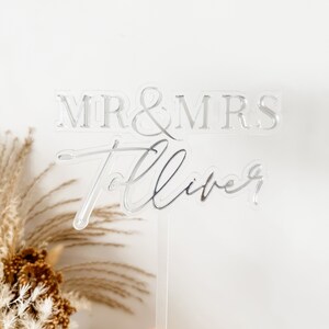 May include: Silver acrylic cake topper with the text "MR & MRS" and "Forever" in a cursive font.