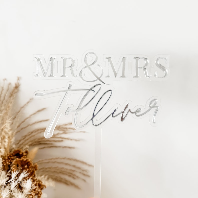 May include: Silver acrylic cake topper with the text "MR & MRS" and "Forever" in a cursive font.
