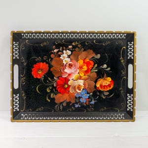 May include: A black metal serving tray with a gold rim and a hand-painted floral design. The flowers are red, orange, yellow, pink, and blue.