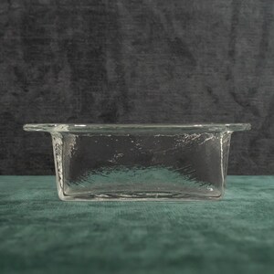 May include: A clear glass rectangular baking dish with a textured surface. The dish has rounded edges and a slightly raised lip.