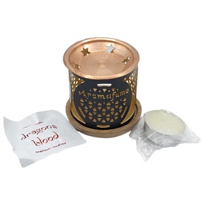 Peut inclure: Un brûleur d'encens en métal noir avec un dessus en cuivre et une base en bois. Le brûleur a un motif en forme d'étoile et les mots "Aromalifume" sont imprimés sur le côté. Une petite bougie chauffe-plat blanche est incluse dans un sac en plastique. Un petit sachet blanc avec les mots "Dragons Blood Premium Incense" est également inclus.