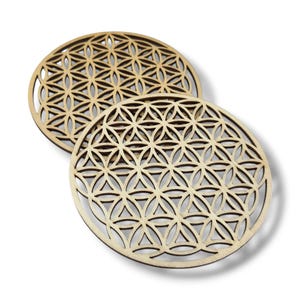 Peut inclure: Deux sous-verres en bois avec un motif géométrique de la fleur de vie. Les sous-verres sont ronds et de couleur brun clair.