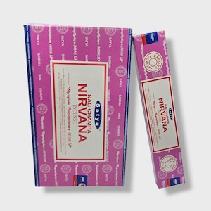 Peut inclure: Deux boîtes d'encens Satya Nag Champa Nirvana. La plus grande boîte est rose avec le texte "Nirvana Incense" et "Nag Champa". La plus petite boîte est rose et blanche avec le même texte et un poids net de 15g.