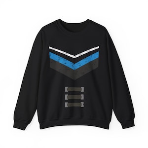 May include: Black sweatshirt with a distressed chevron design in white, blue, and gray. Below the chevron are three horizontal gray bars. The sweatshirt is a casual, long-sleeved garment.