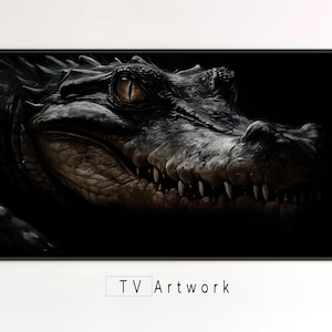 Puede incluir: Obra de arte enmarcada que muestra un primer plano de la cabeza de un caimán. El caimán tiene piel oscura y texturizada, dientes visibles y ojos amarillos intensos. La obra está etiquetada como "TV Artwork" en la parte inferior.