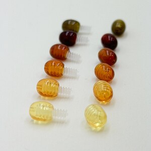May include: Assortment of small, colorful, plastic, screw-on eyes with a honeycomb pattern. The eyes are in various shades of brown, orange, and green.