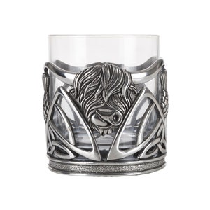 May include: A silver Highland Cow design whisky glass with a Celtic knot pattern. The glass is clear and has a silver rim.