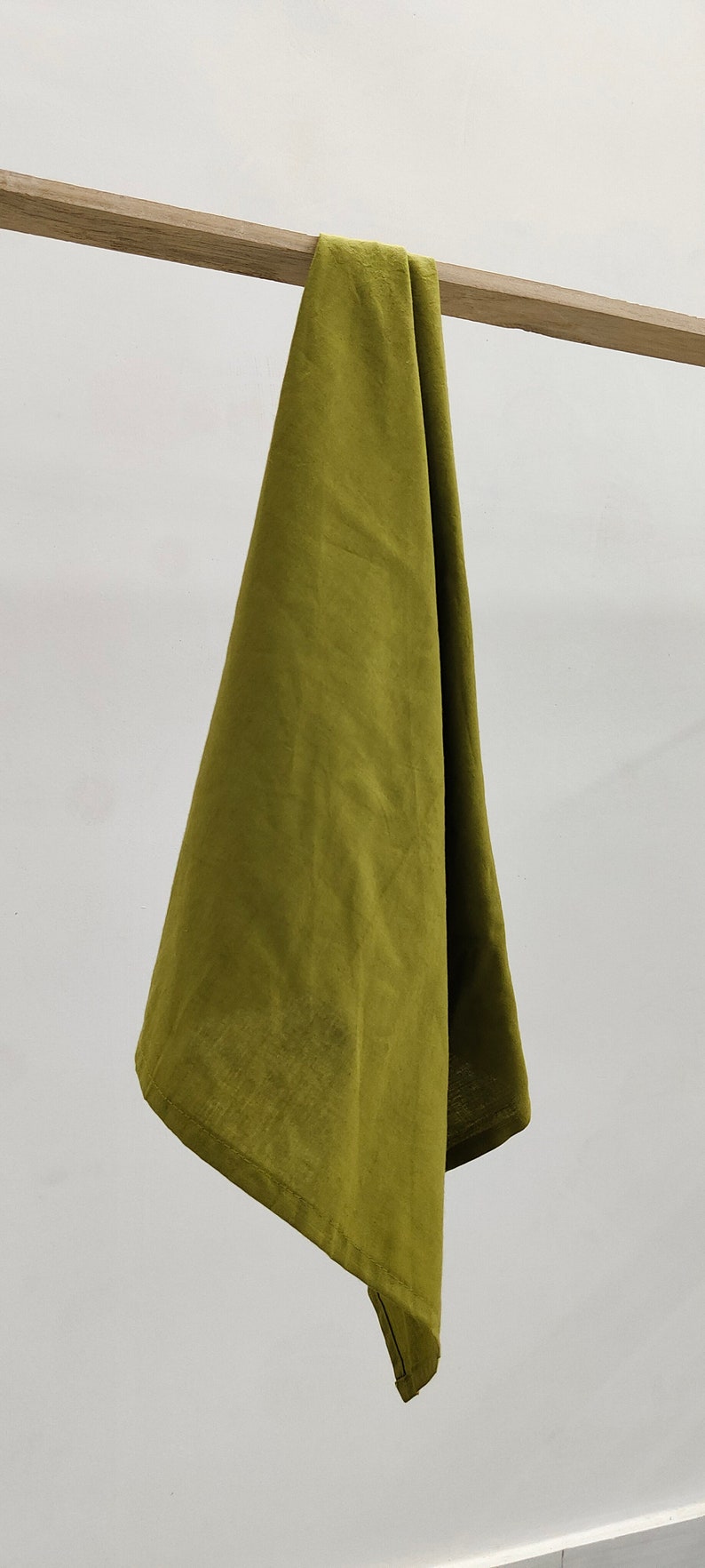 May include: A folded olive green linen kitchen towel hanging on a wooden rod.
