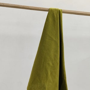 May include: A green fabric kitchen towel hanging on a wooden rod.