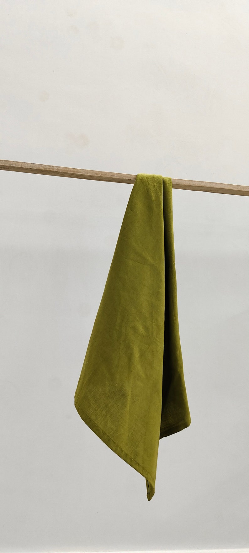 May include: A green fabric kitchen towel hanging on a wooden rod.