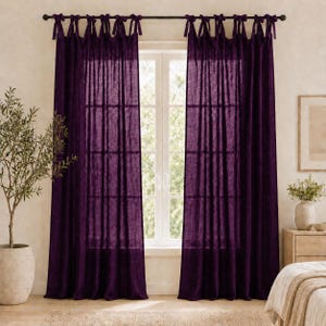 Puede incluir: Un par de cortinas de color morado intenso que cuelgan de una barra de metal oscuro. Las cortinas presentan un diseño de lazos con cintas de tela anudadas en la parte superior, creando un efecto fruncido. La tela es semitransparente.