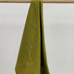 May include: A folded olive green linen kitchen towel hanging on a wooden rod.