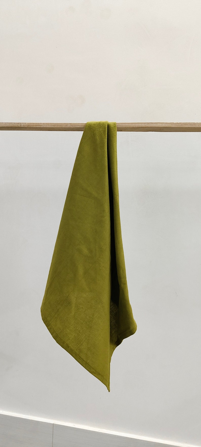 May include: A folded olive green linen kitchen towel hanging on a wooden rod.