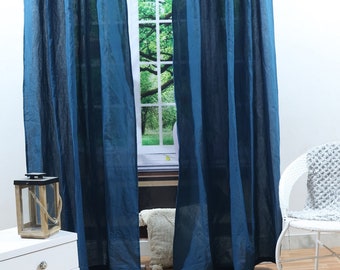 May include: A pair of dark blue linen curtains hanging in a window. The curtains are gathered at the top and have a relaxed, casual look.