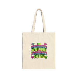 May include: A cream-coloured tote bag featuring the text "Chronically Online, Emotionally Offline" in a vibrant, retro font. The design incorporates rainbow, wifi, battery, and heart icons. The bag has two handles.