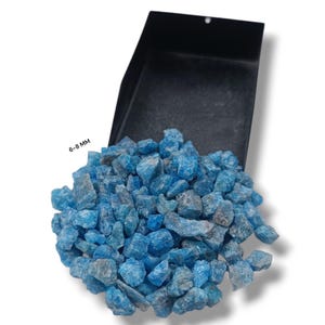 May include: A pile of bright blue, rough-cut stones spilling from a black container. The stones are a vibrant turquoise color, with a few gray undertones. The text "6-8 MM" is visible in the image. These stones are likely used for decorative purposes.