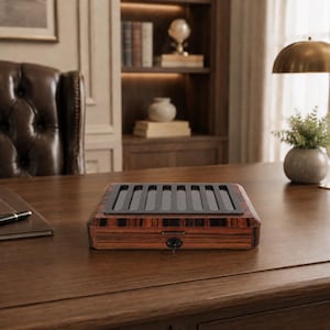 May include: A rectangular wooden storage box with a dark brown striped grain pattern. The top features a black panel with eight vertical slots. A small circular keyhole is centered on the front edge of the box, which is closed and locked.