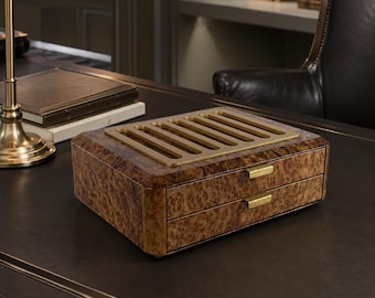 Könnte beinhalten: Eine rechteckige Aufbewahrungsbox aus Holz mit Maserung, ausgestattet mit zwei Schubladen mit horizontalen messingfarbenen Metallgriffen und einer geschlitzten messingfarbenen Metallplatte auf der Oberseite.